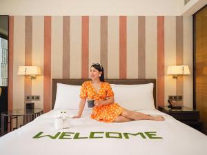 a woman in an orange dress sitting on a bed at DoubleTree by Hilton Sukhumvit Bangkok in Bangkok