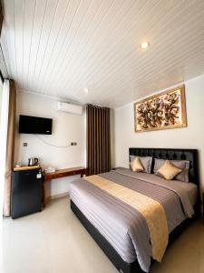 a bedroom with a large bed and a tv at Pondok Biu 2 in Denpasar