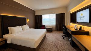 a hotel room with a bed and a desk and a computer at Impiana Hotel Ipoh in Ipoh