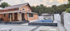 a brick house with a pool in front of it at Vriksha Heritage Farm Stays in Sethumadai