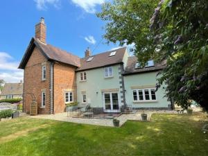 a large brick house with a grass yard at Elm Cottage in Alvescot