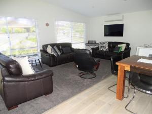 a living room with leather furniture and a flat screen tv at Ripplesea in Port Moonta