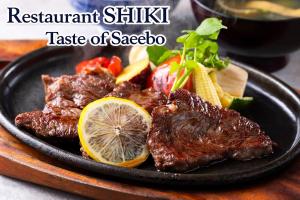 a black plate with steak and vegetables on a table at ART HOTEL Sasebo Central in Sasebo