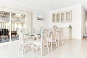 a white dining room with a glass table and chairs at The Stately Way in Wallaroo