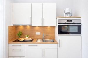 a kitchen with white cabinets and a sink at Ille in Wittdün