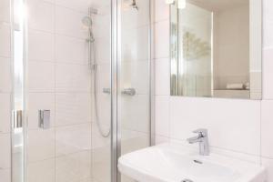 a white bathroom with a shower and a sink at Ille in Wittdün +11 photos