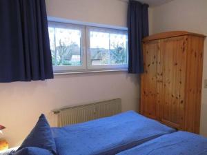 a bedroom with a blue bed and a window at Hygge in Nebel