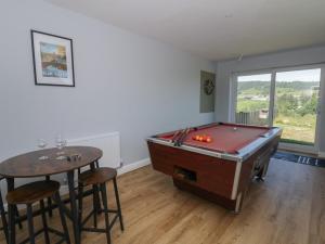 a room with a pool table and a table with stools at Glanyrafon Bungalow in Rhayader
