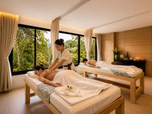 a woman standing in a room with three beds at Duplex Loft 5 Pools and Gym near Nai Harn Beach- UTL B119 in Rawai Beach