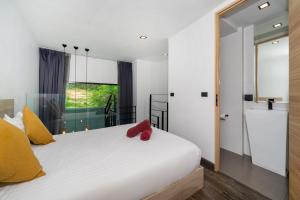 a bedroom with a white bed with yellow and red pillows at Duplex Loft 5 Pools and Gym near Nai Harn Beach- UTL B119 in Rawai Beach +16 photos