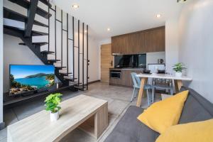 a living room with a staircase and a kitchen at Duplex Loft 5 Pools and Gym near Nai Harn Beach- UTL B119 in Rawai Beach