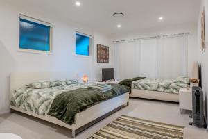 a bedroom with two beds and a television in it at Serenity Rainforest Retreat With Breathtaking Gold Coast Views - Sleeps 4 - 6 people in Springbrook