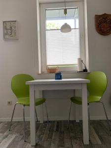 a table with two green chairs and a window at HaK-3 in Wittdün