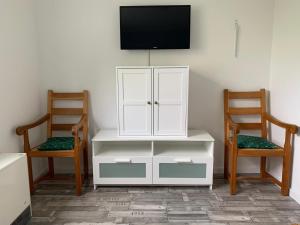 a white cabinet with a tv on a wall with two chairs at HaK-3 in Wittdün