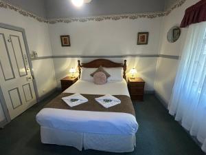 a bedroom with a bed with two towels on it at Foundry Cottages in Rutherglen