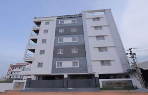 a tall white building with a sign on it at Hotel Vibrama in Tirupati