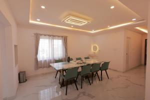 a dining room with a table and green chairs at Hotel Vibrama in Tirupati