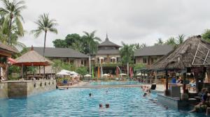 a pool at a resort with people in it at Club Bali Suite Legian in Legian