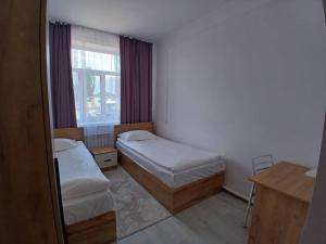 a small room with two beds and a window at Archa Hotel Kochkor in Kochkorka +6 photos