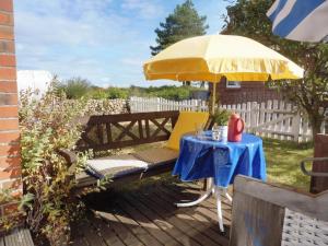 a table with a yellow umbrella and a table with a chair at Muschel in Wittdün