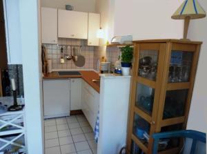 a small kitchen with white cabinets and a wooden shelf at Muschel in Wittdün