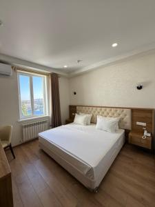 a bedroom with a large white bed with a window at Safia Plaza Hotel in Bukhara +31 photos