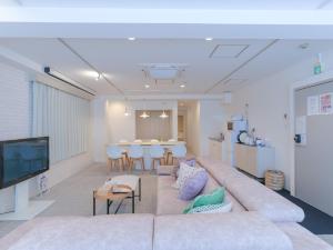a living room with a large couch and a table at INOVE VILLA OSAKA -120m2 , 7 Double Beds , 2 BR , 2 Bath , Easy Access to Umeda , Kyoto ーPerfect for Families & Groupsー in Osaka