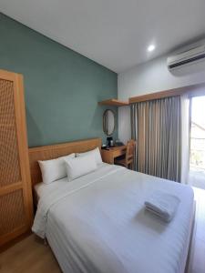 a bedroom with a large white bed and a desk at Griya Yunika in Yogyakarta