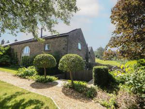 a brick house with bushes in front of it at Overlea Cowshed in Birch Vale