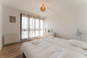 a white bedroom with a large bed and a window at A350 Suites - Appartement climatisé, 2 chambres in Colomiers