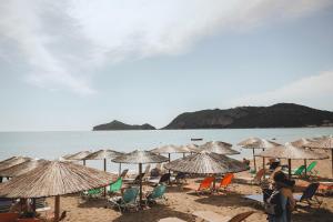 eine Gruppe von Stühlen und Sonnenschirmen an einem Strand in der Unterkunft Azure Mare Studios in Agios Georgios Pagon