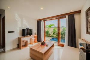 a living room with a tv and a large window at The Solas Villa Ubud in Ubud