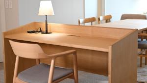a wooden desk with a lamp and a chair at ジローズガーデン in Ishinomaki