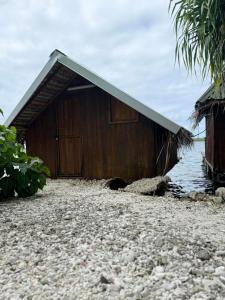a wooden building on a rocky beach next to the water at Faimano Lodge & Car in HUH