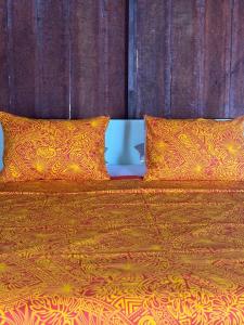 an orange bed with two pillows and avertisement at Faimano Lodge & Car in HUH