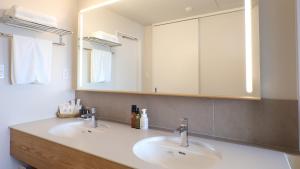a bathroom with two sinks and a large mirror at ジローズガーデン in Ishinomaki