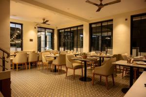 a restaurant with tables and chairs and windows at Barefoot bliss by iLiF Hotels in Revadanda