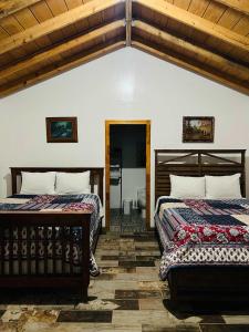 two beds in a room with wooden ceilings at #11- Rancho Meling in Camalú