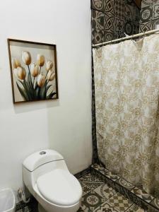 a bathroom with a toilet and a painting of flowers at #11- Rancho Meling in Camalú +1 photo