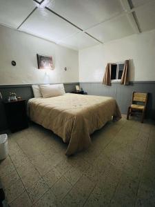 a bedroom with a large bed and a chair at Rancho Meling in Camalú