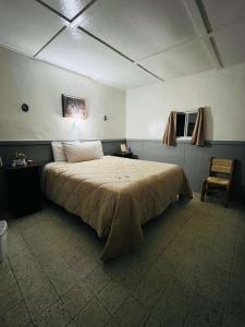 a bedroom with a large bed and a chair at Rancho Meling in Camalú