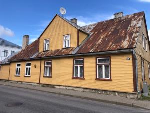 a yellow house with a rusty roof on a street at Rohu Külaliskorter vanalinnas in Kuressaare