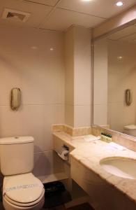a bathroom with a toilet, sink, and mirror at Macau Masters Hotel in Macau