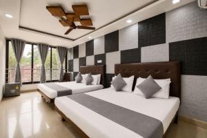 two beds in a room with two windows at MogPrach Boutique in Calangute