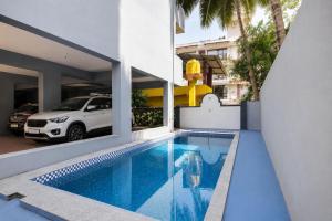 a swimming pool in front of a house with a car at MogPrach Boutique in Calangute