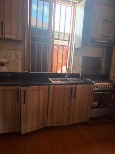 a kitchen with a sink and a window and a stove at Kigali Alba Home in Kigali