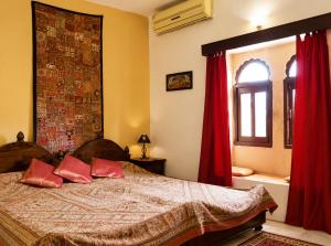 a bedroom with a bed with red curtains and a window at Killa Bhawan Lodge in Jaisalmer