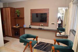 a living room with two green chairs and a television at HOTEL THIRD EYE bY RAMANA TOWERS in Tiruvannāmalai