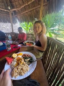 a woman sitting at a table with a plate of food at Janibichi Adventures hostel in Moshi