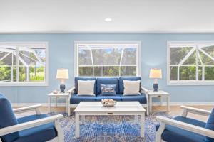 a blue living room with a blue couch and two windows at Murmond- Captiva Home in Captiva